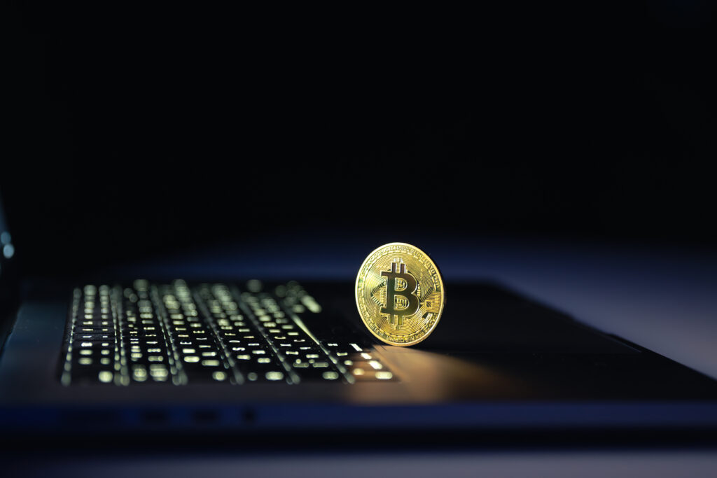 Bitcoin coin near laptop on black background. Finance and crypto money concept.