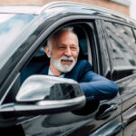 Mature man wearing business suit driving a car
