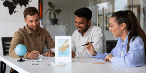 Three people engaged in discussion at a table, with a globe placed in the center, symbolizing global topics.